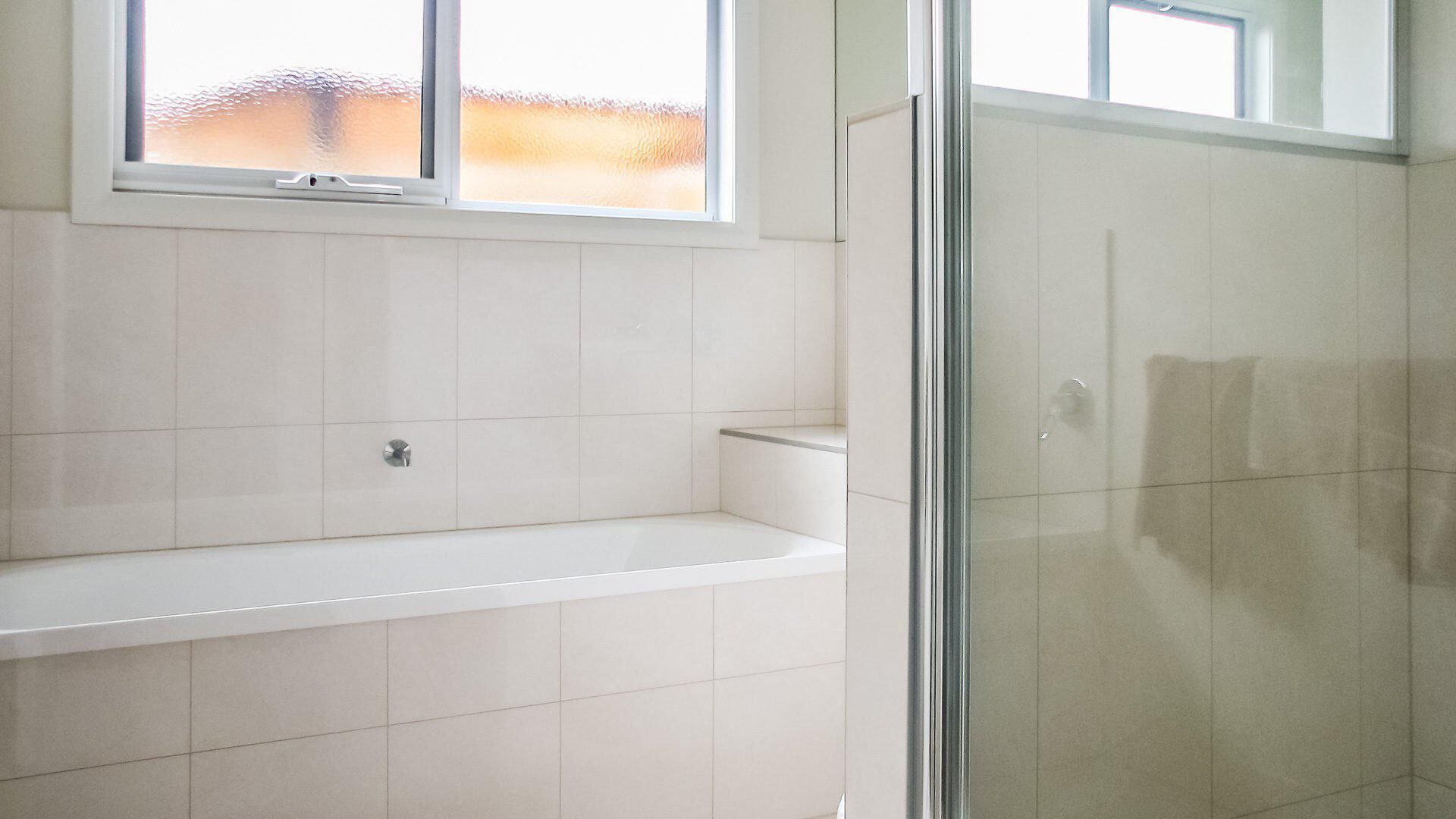 A bathroom with a bathtub, a shower area, and a window.
