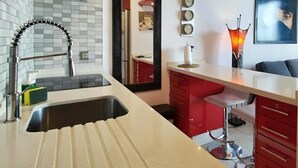 A modern kitchen with a large island, red cabinetry, and a mirror.