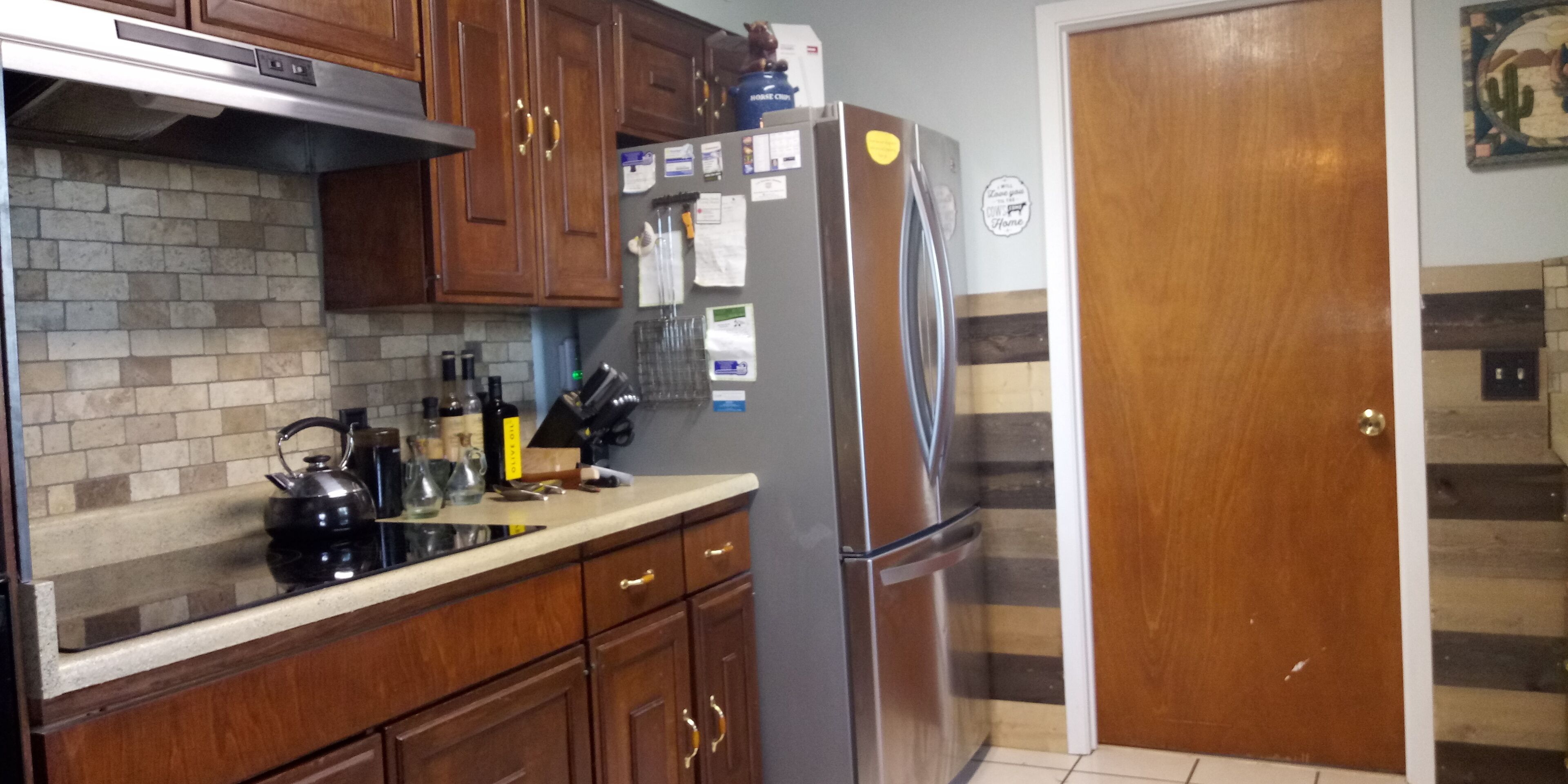 Una cocina con armarios de madera, un refrigerador de acero inoxidable y salpicadero de azulejos.