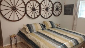 A bedroom with a bed, striped bedding, and four large wooden wheels on the wall.