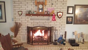 A living room with a fireplace, a clock, and various decorations on the wall.