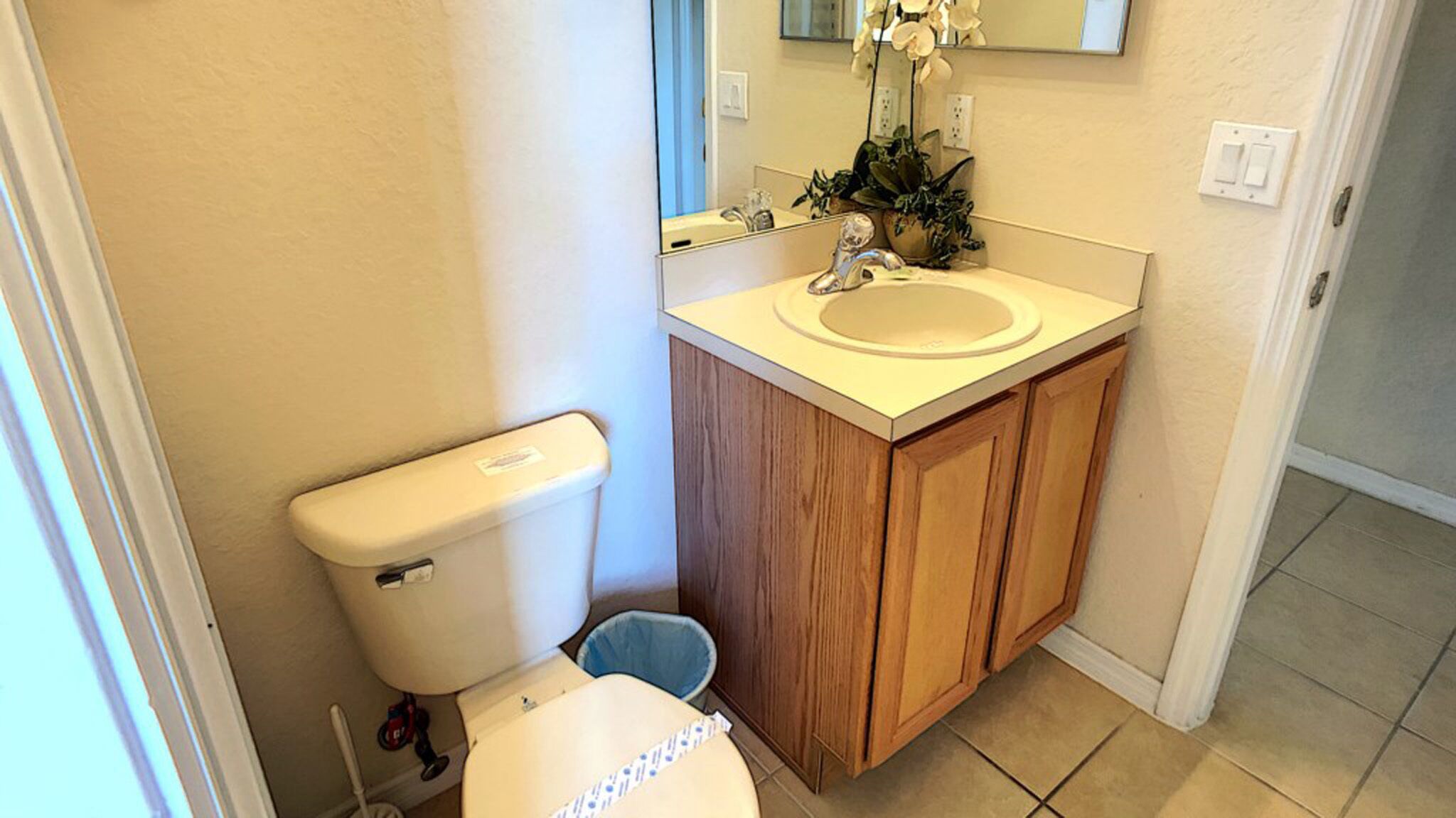 A small bathroom with a toilet, sink, and mirror.