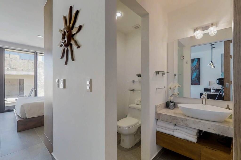 Une salle de bain moderne avec un grand miroir, un lavabo blanc et des toilettes.