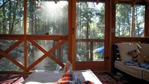 A room with a large window, a bed, a couch, and a dog. - Idyllbrook: Mission-style gem with a screened BrookHouse gazebo & EV charger. (Idyllwild-Pine Cove)