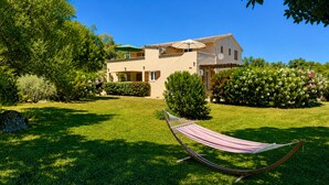 A house with a garden, a hammock, and a clear blue sky.