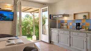 A kitchen with a TV, a coffee maker, and a tablet on the counter.