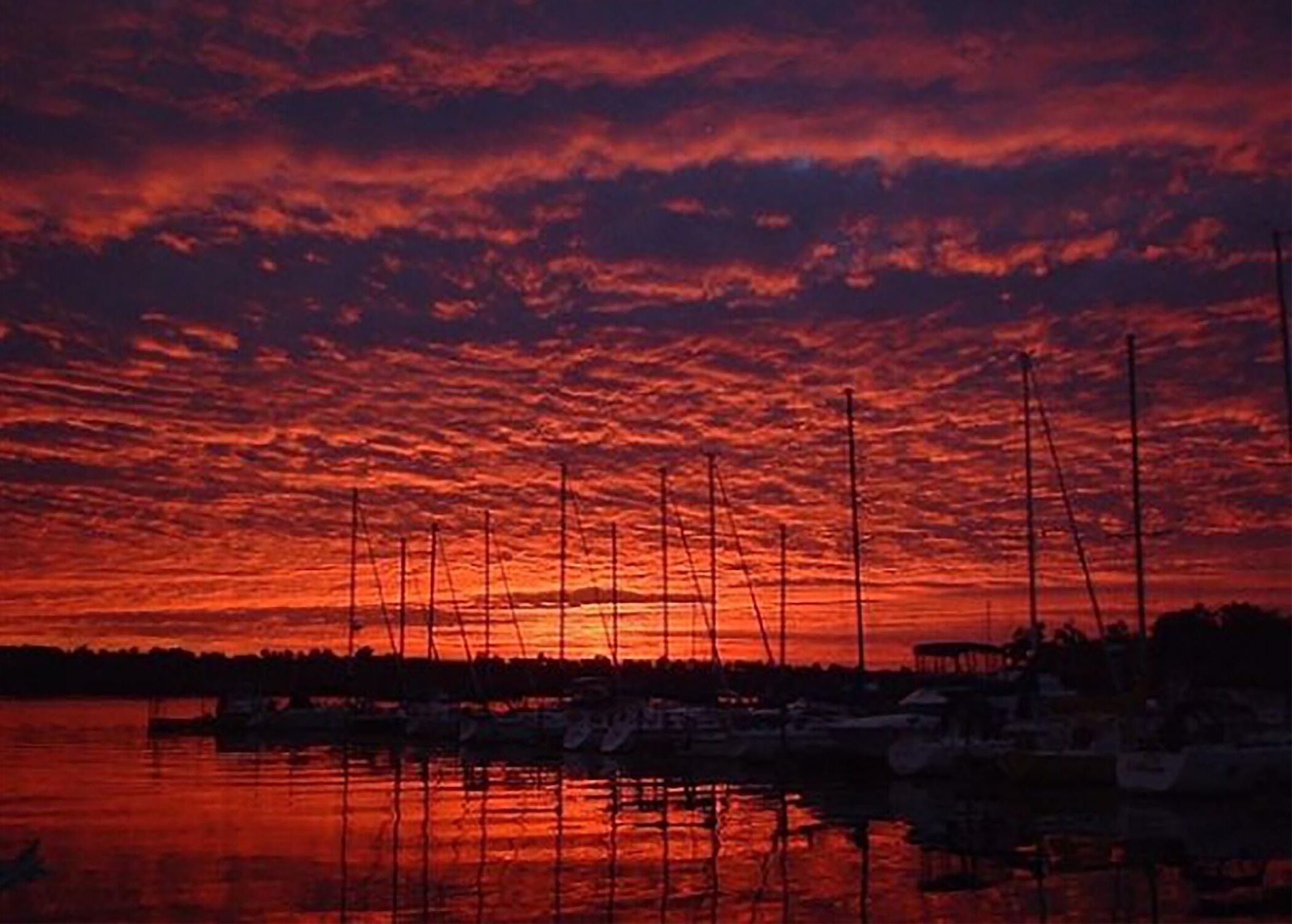 A sunset over a marina with boats docked.