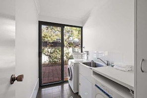 Una cocina compacta con lavadora, un lavamanos y una pequeña ventana.