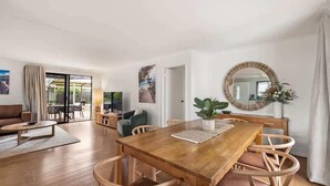 A spacious living area with a wooden dining table, wicker chairs, and a large mirror. - Cormorant Cottage—Garden Beach Abode w/ Game Room (Dunsborough)