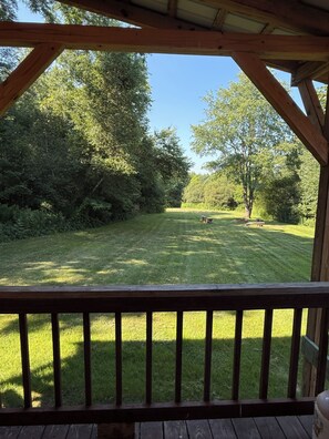 A wooden deck with a view of a well-maintained grassy yard and trees.