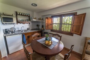 A compact kitchen with a dining area, featuring a microwave, sink, and wooden cabinets.