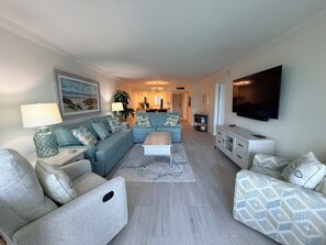 A living room with a sectional sofa, a coffee table, and a TV mounted on the wall.