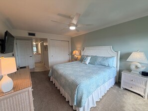 A bedroom with a bed, bedside tables, a ceiling fan, and a television.