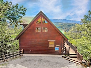 A wooden cabin with a steep staircase, surrounded by lush greenery and mountains in the background. - A Smoky Mtn Dream: Spectacular Views! Home Theater, hot tub, Top Amenities, close to attractions! (Sevierville)