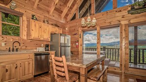 A wooden cabin kitchen with a wooden dining table, chairs, and a refrigerator.