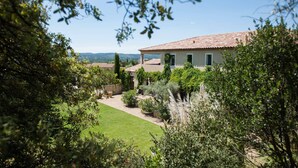 Une maison avec un toit en tuiles, entourée d’une végétation luxuriante et d’une pelouse bien entretenue.