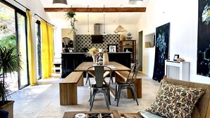 Un salon moderne avec une table à manger en bois, deux chaises, une table basse et un canapé agrémenté d’un coussin à motifs.