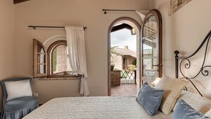 Une chambre avec un grand lit, une fenêtre avec des rideaux, une vue sur l’extérieur et un balcon.