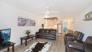 A modern living room with leather sofas, a flat-screen TV, and a cowhide rug.