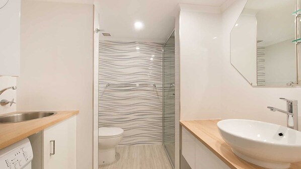 Une salle de bain moderne équipée d’une douche, de toilettes et d’un lavabo.