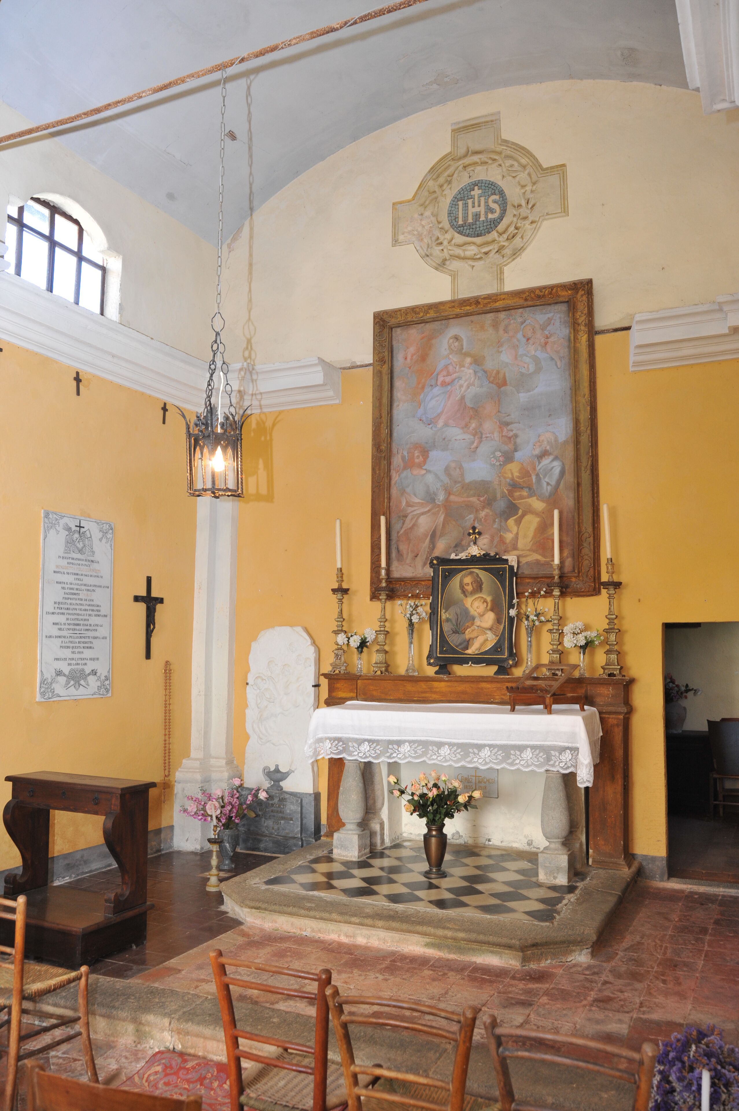 A church interior with a large religious painting, a wooden altar, and a checkered floor.
