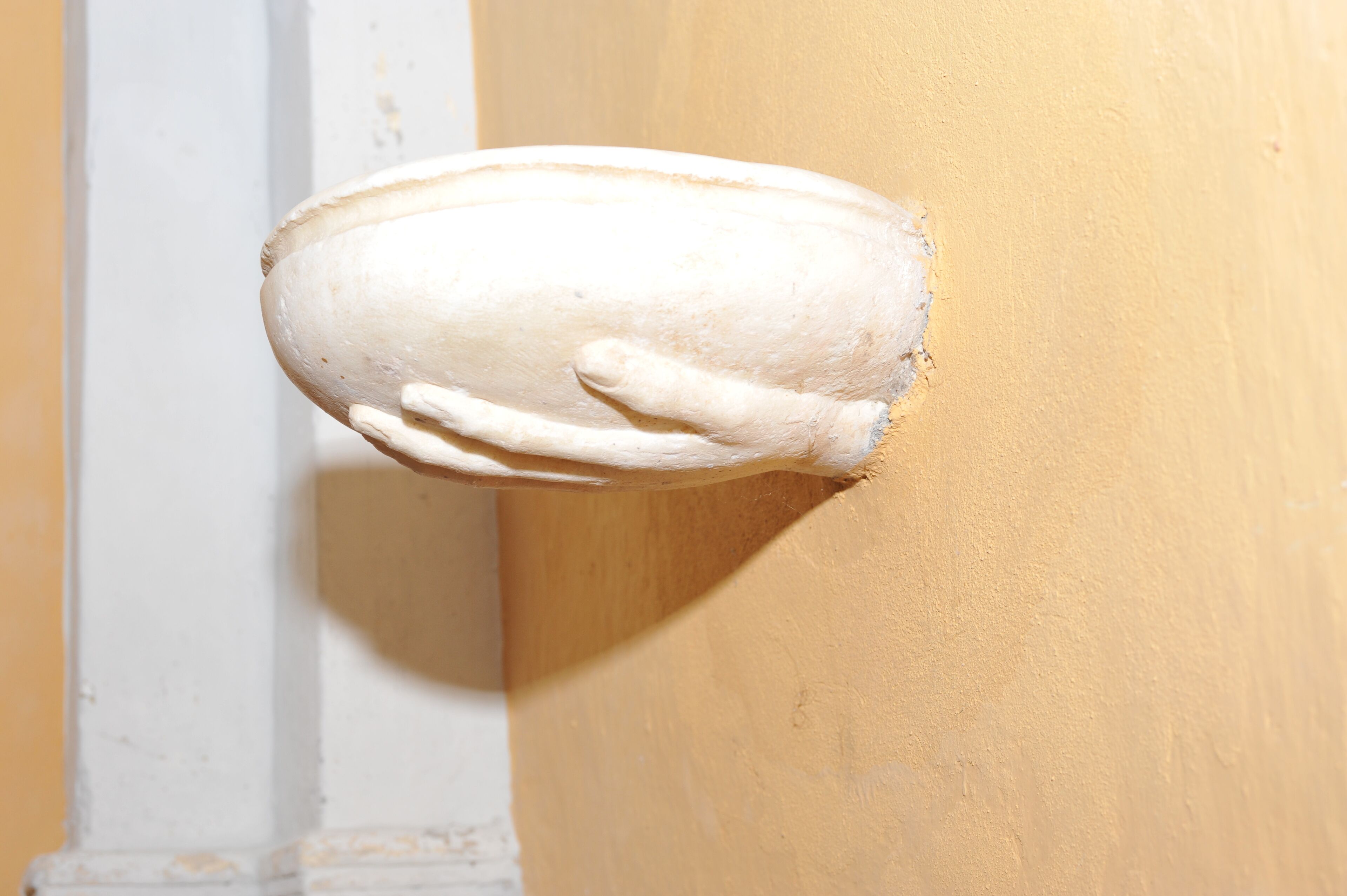 Un objeto blanco y texturizado, fijado a la pared, con forma de mano.