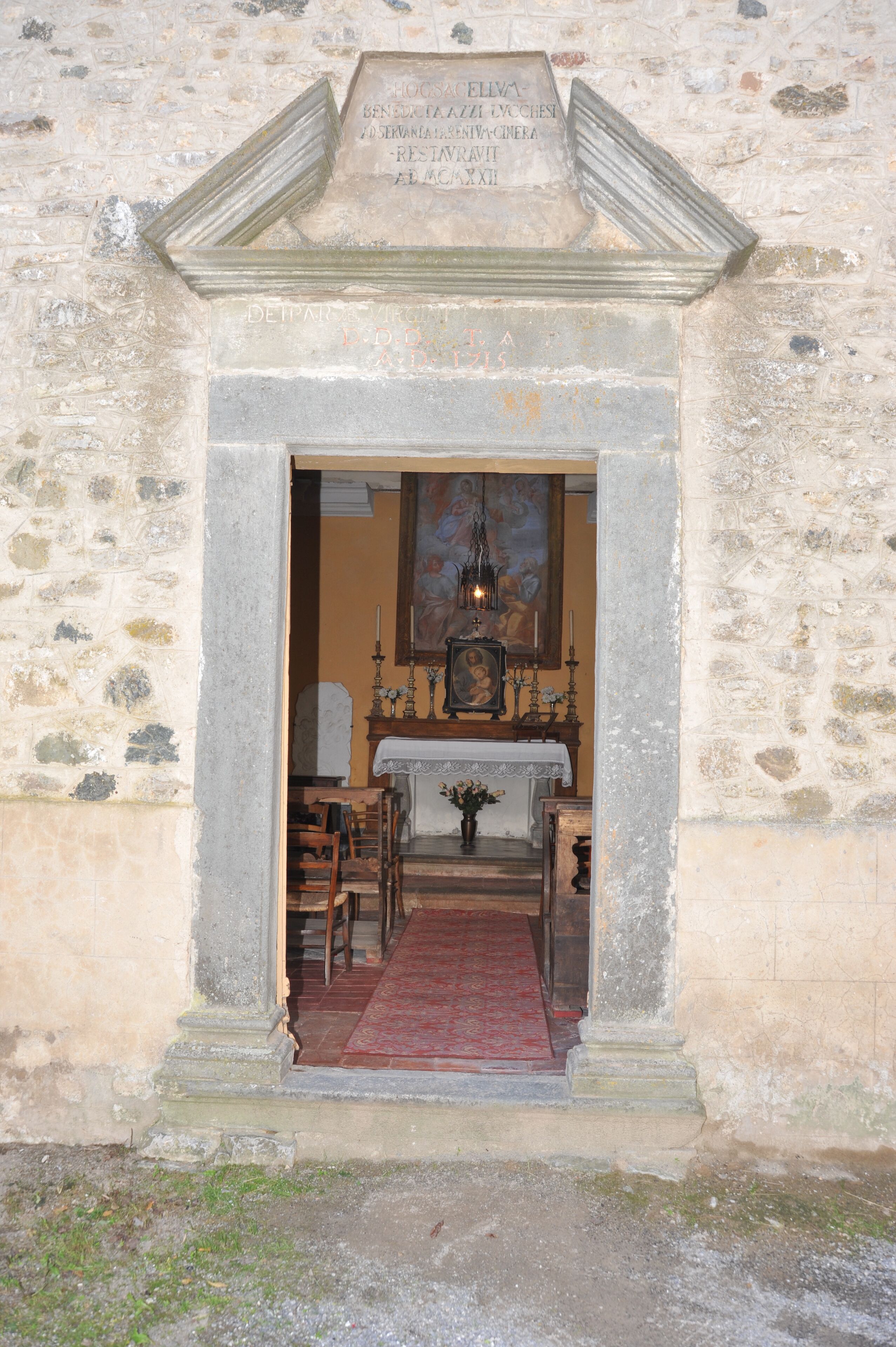 Un arco de piedra que da paso a una habitación con un banco de madera, una mesa y un cuadro enmarcado en la pared.