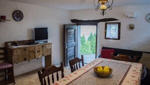 Ein gemütlicher Essbereich mit einem Holztisch, Stühlen, einem Fernseher auf einer Holzkommode und einer Schüssel Äpfel auf dem Tisch.