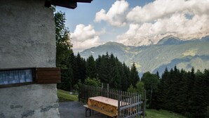 Eine rustikale Holzbank vor einem Gebäude mit Blick auf die Berge.