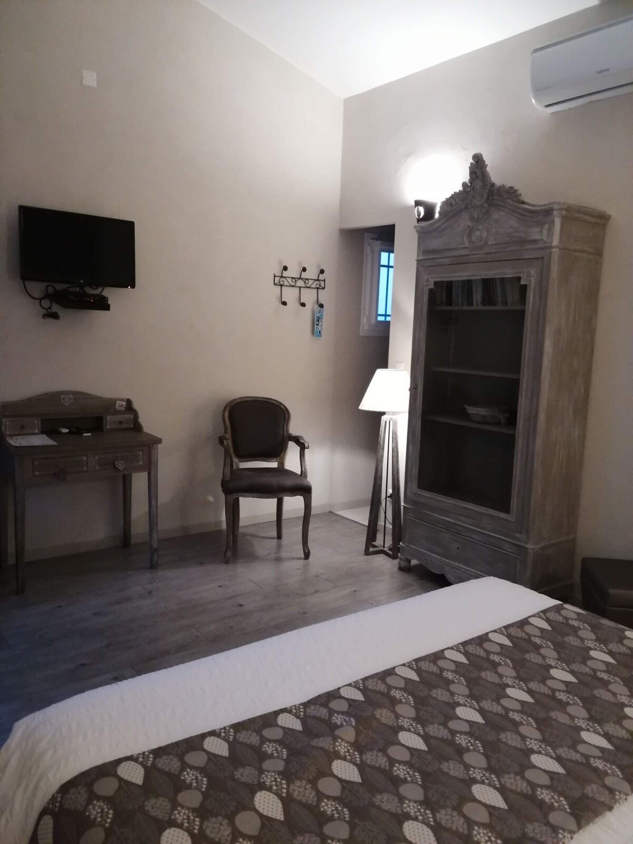 Ein Schlafzimmer mit einem Bett, einem Schreibtisch, einem Stuhl, einem Fernseher und einem Kleiderschrank.