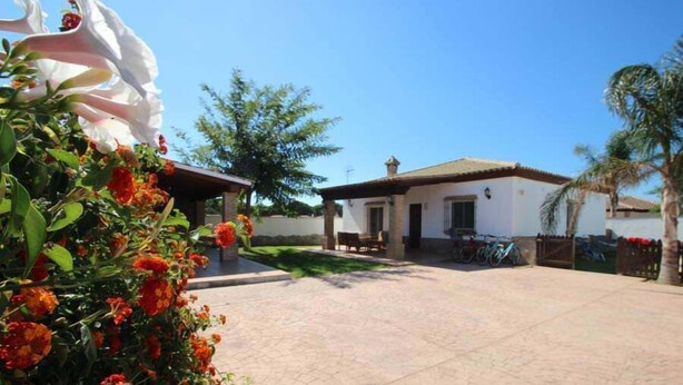 Un patio con un edificio blanco, un área de estar techada y una bicicleta.