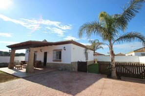 A house with a patio, a covered area with furniture, and a palm tree. - Large pool area, 4 bikes, free Wi-Fi, 2 parking spaces - Casa Anita - (Conil de la Frontera)
