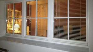 A set of windows with white frames and wooden blinds.