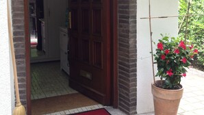 A wooden door with a red mat, a potted plant, and a doormat with a castle logo.