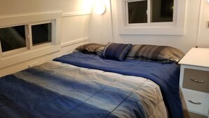 Une chambre à coucher avec un lit, une table de chevet et une fenêtre.