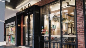 Das AMIGO Hotel mit Glasfassade, Backsteinfassade und einem sichtbaren Innenbereich mit Sitzgelegenheiten.