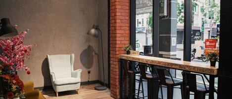 A bar area with a brick column, a white chair, and a bar counter with stools.