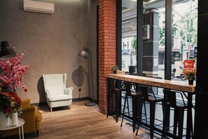 A bar area with a brick column, a white chair, and a bar counter with stools. - Amigo Hotel Miri (Miri)