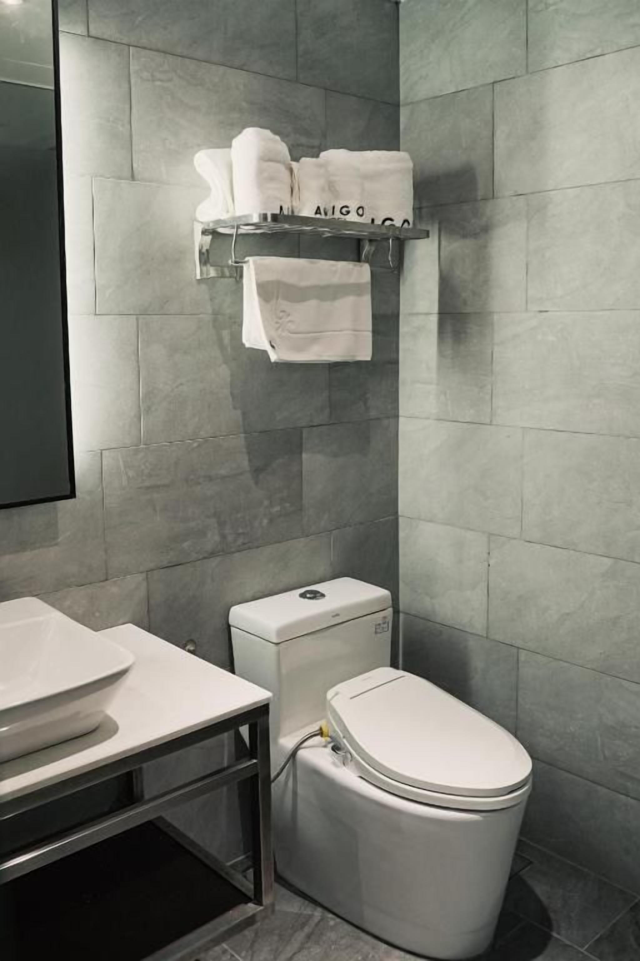 A modern bathroom with a toilet, sink, and towel rack.