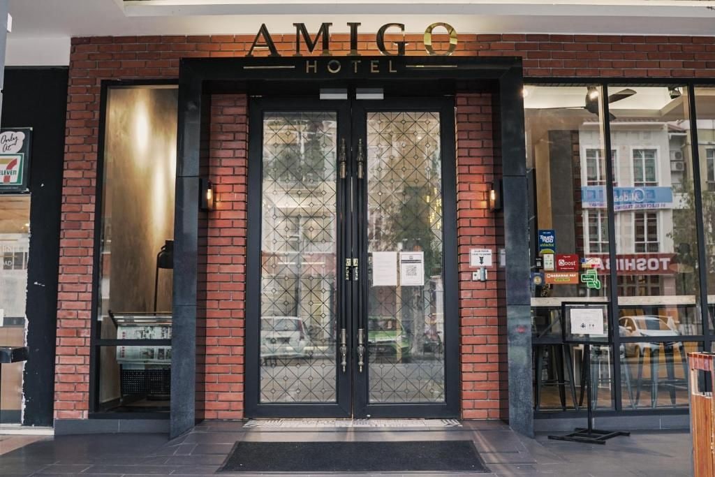 The exterior of the Amigo Hotel with a brick facade, double doors, and a visible entrance.