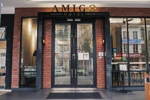 The exterior of the Amigo Hotel with a brick facade, double doors, and a visible entrance.