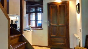 A wooden staircase leading to a kitchen with a window and a door. - Hutterite Home Apartment - Full comfort, close to Bratislava, Vienna, and Brno. (Velké Leváre)
