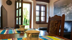 A dining area with a table set for two, featuring a clock on the wall and a view of a cityscape through a window. - Hutterite Home Apartment - Full comfort, close to Bratislava, Vienna, and Brno. (Velké Leváre)