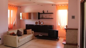 A living room with a sofa, a coffee table, a TV, and a cabinet with decorative items.