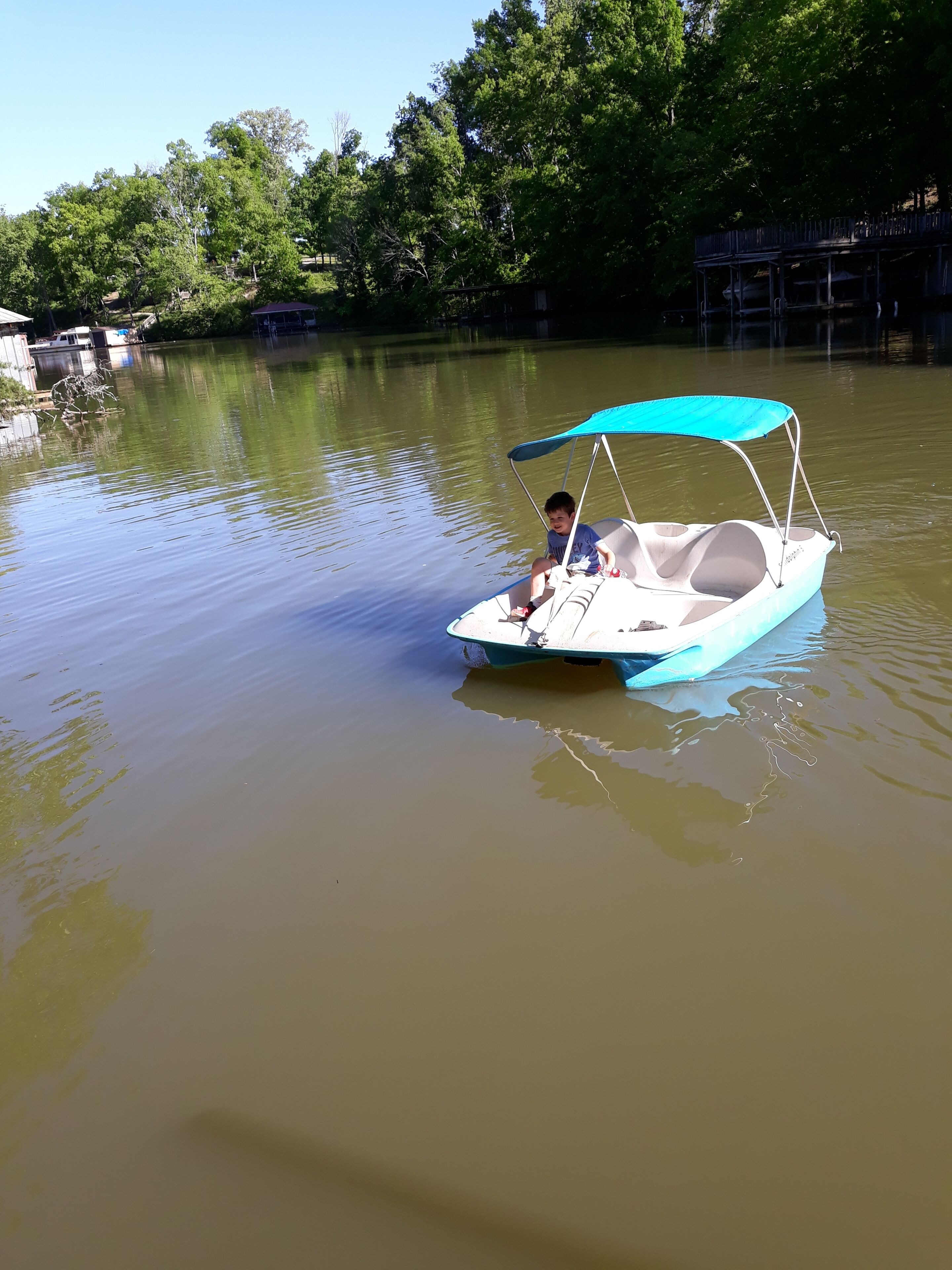 A small boat with a canopy on a calm river.