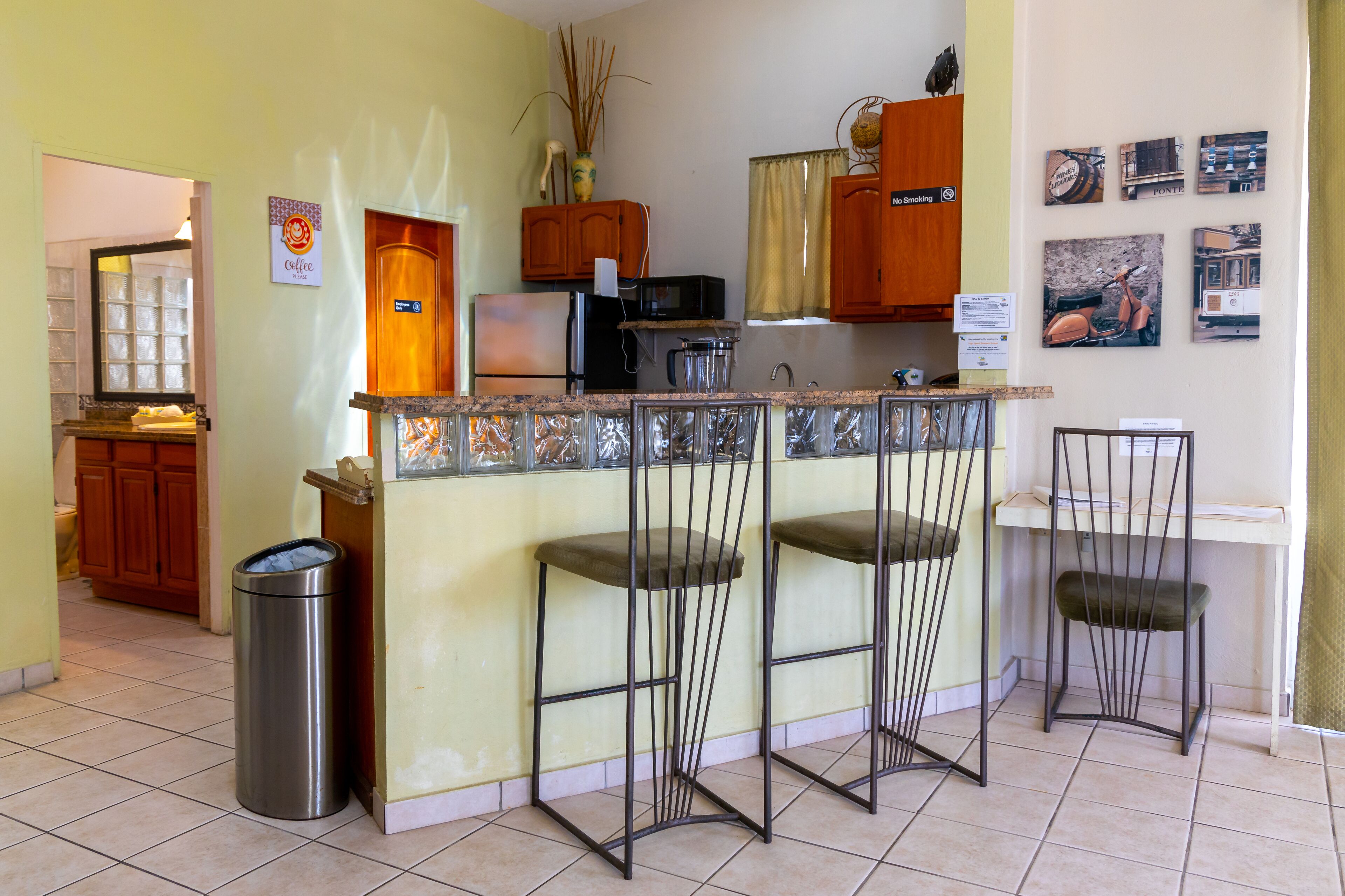 A compact kitchen with a central island, bar stools, and a trash bin.