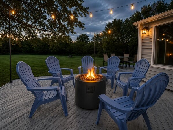 Eine Terrasse mit Feuerstelle und Adirondack-Stühlen.
