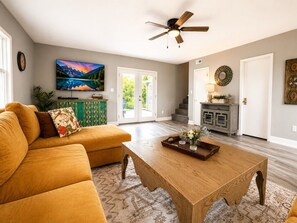 A living room with a sofa, coffee table, and a television. There is a staircase leading to another level.