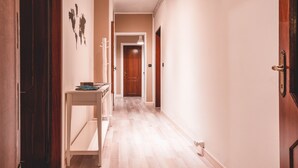 A hallway with a wooden floor, a white console table, and a door at the end.
