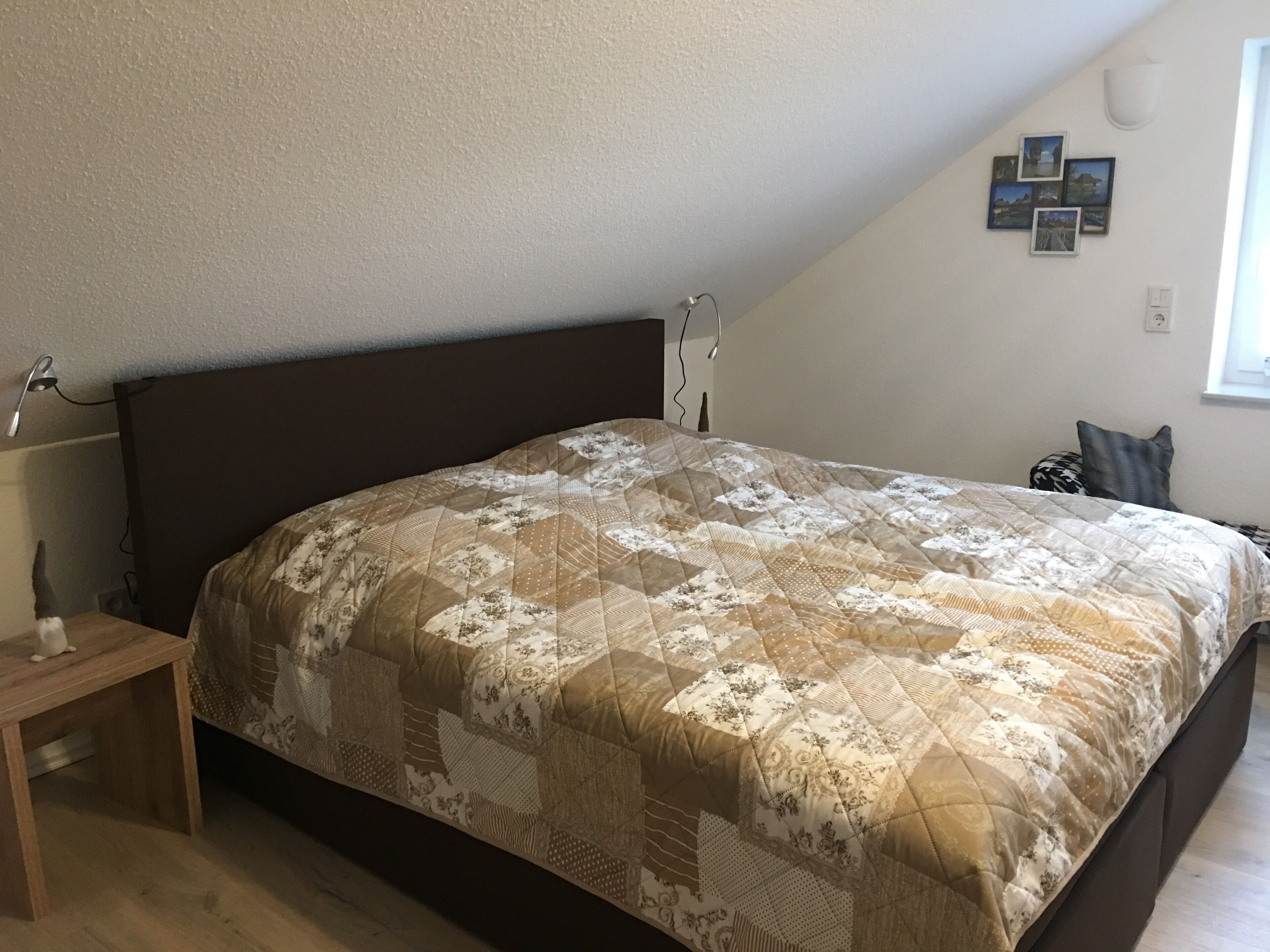 Ein Schlafzimmer mit einem großen Bett, einem Nachttisch, einer Wandlampe und einem Fenster mit Blick.